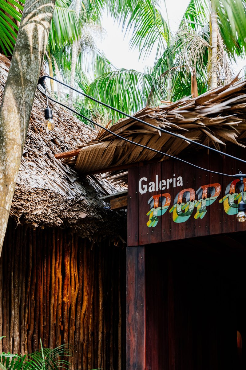 Exterior storefront with layered palm thatch roof and bamboo facade framed by palm fronds