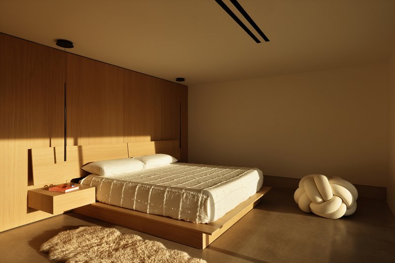 Bedroom with platform bed and timber wall panels in warm afternoon light
