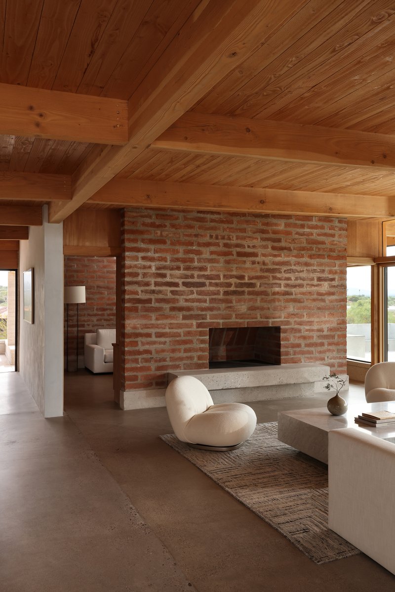 Brick fireplace wall meeting timber paneling under vaulted ceiling with diagonal wood planking