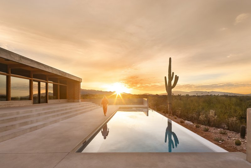 Reflecting pool with concrete deck and saguaro cactus at sunset in the desert landscape