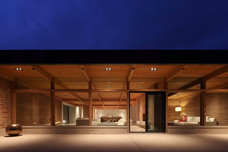 Coffered timber ceiling and full-height glazing framing the interior living spaces at night