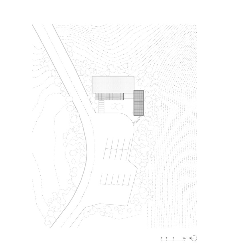 Site plan drawing showing two building volumes beside a curved driveway and topographic contour lines