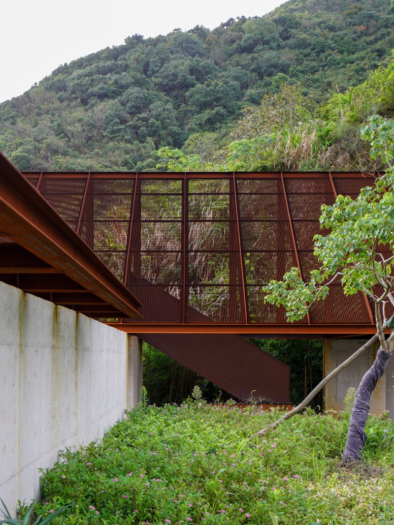 Elevated steel bridge spanning concrete retaining walls nestled into a forested hillside