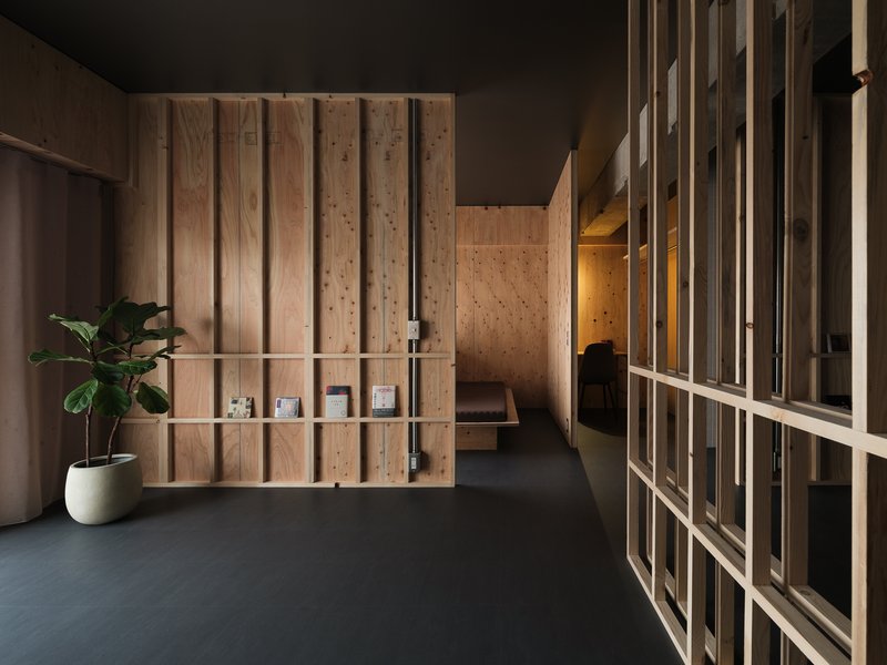 Reception area with vertical timber slat partitions and floating display shelves beside a potted plant