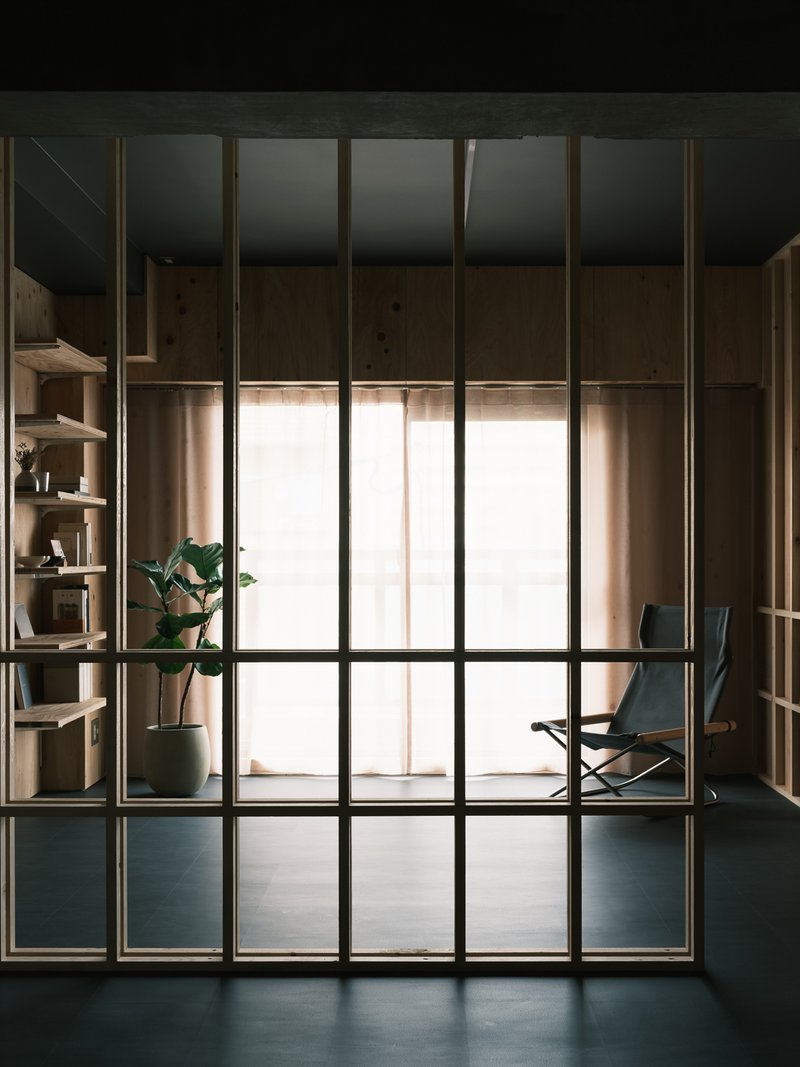 Full-height steel and glass partition framing a view into a timber-lined space with daylight filtering through curtains