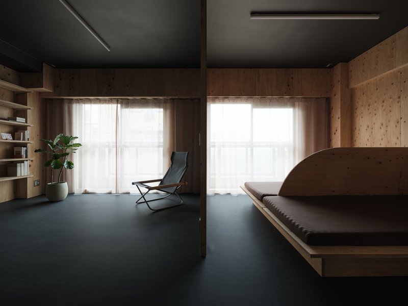 Open living area with timber walls, dark grey rubber flooring, and sheer curtains over glazed openings