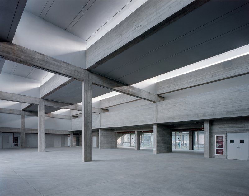Concrete post-and-beam system with continuous clerestory glazing and view through to adjacent courtyard at dusk