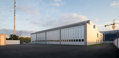 This architectural image showcases a modern industrial building with a minimalist design. The buildi