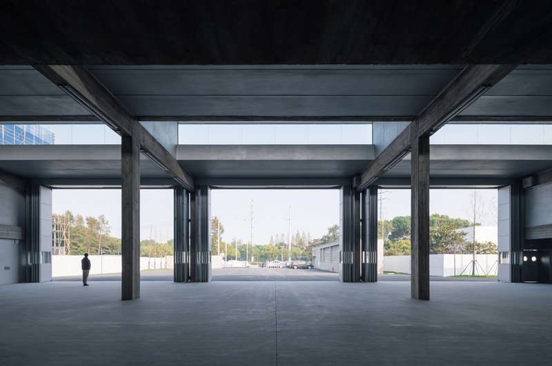 Ground floor interior with exposed steel columns and beams framing views to the outdoor courtyard