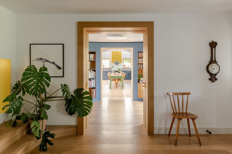 Oak-framed doorway leading through aligned rooms with monstera plant and antique barometer on wall