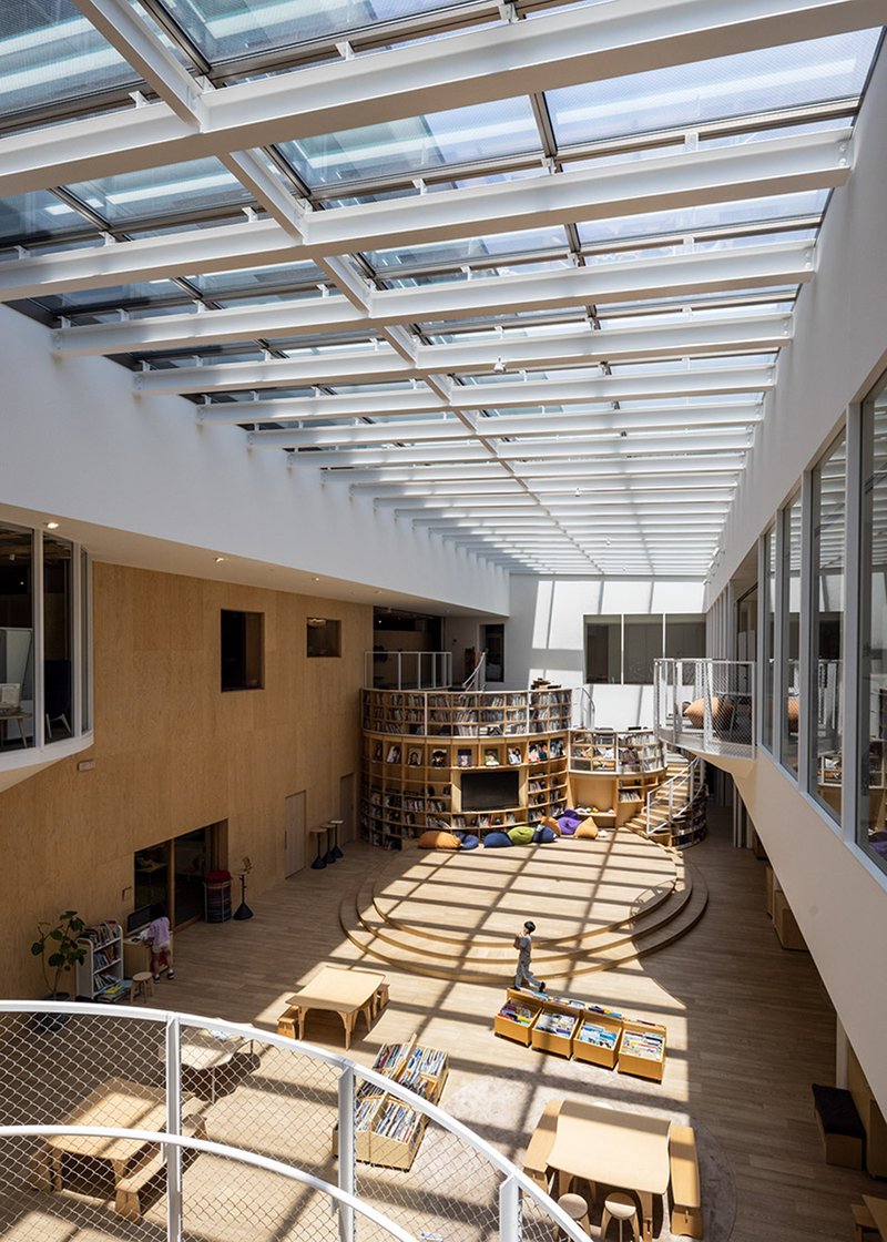 View from mezzanine showing striped sunlight pattern across timber floor and circular reading platform