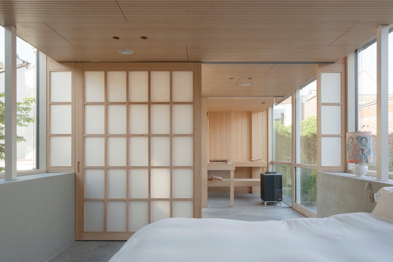 Bedroom with translucent sliding shoji screens and timber slatted ceiling opening to adjacent spaces