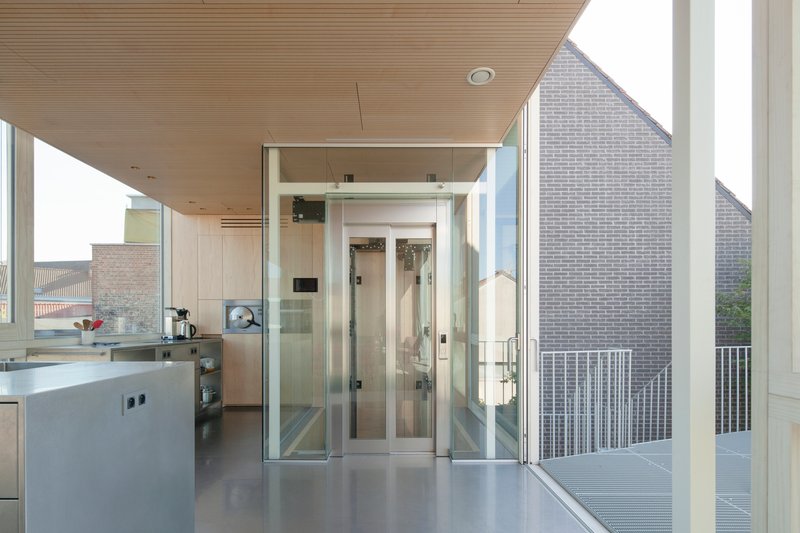 Kitchen with glass elevator shaft opening to balcony overlooking neighboring brick facades