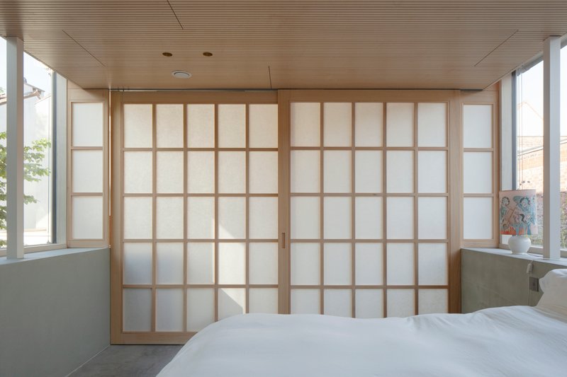 Closed shoji screen wall with timber grid frames and translucent panels in afternoon light
