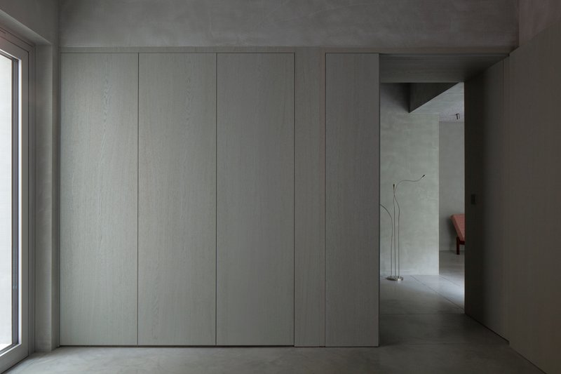 Flush white paneled wall with concealed joints adjacent to concrete floor and window