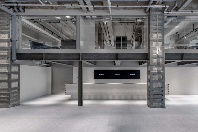 Interior view of double-height space with exposed concrete columns, steel beams, and central service counter