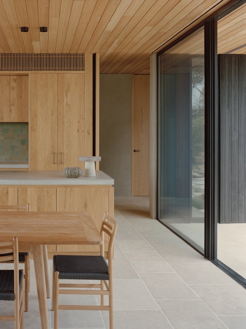 Kitchen interior with timber-lined ceiling and sliding glass doors leading to an exterior courtyard