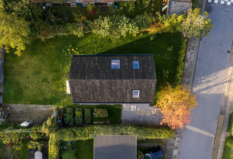 Overhead view of the vertical-clad pitched roof with three skylights surrounded by garden and driveway