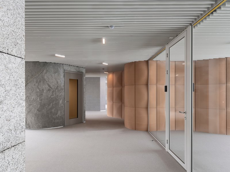 Entrance corridor with glass door, grooved timber wall panels, exposed concrete, and slatted ceiling