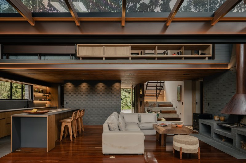 Double-height living area with timber mezzanine, textured concrete block wall, and clerestory windows filtering daylight