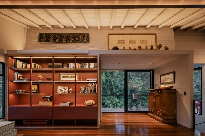 Built-in shelving with terracotta-painted interior backing beneath horizontal timber ceiling with exposed beams