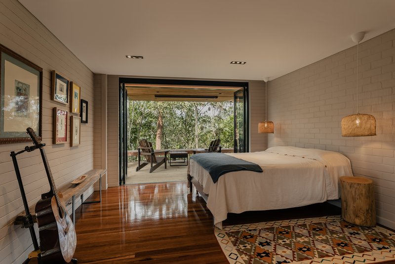 Bedroom with folding glass doors opening to a covered terrace among the trees