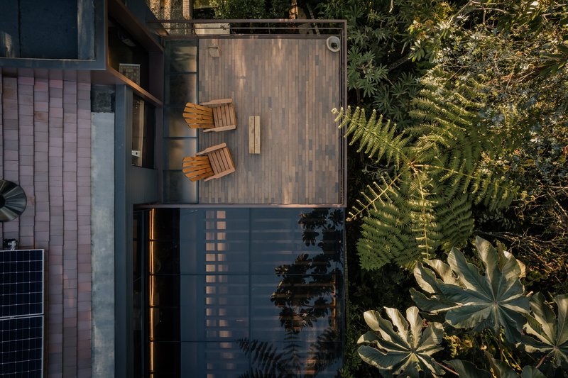 Aerial view of timber deck terrace with two folding chairs beside ferns and tropical foliage
