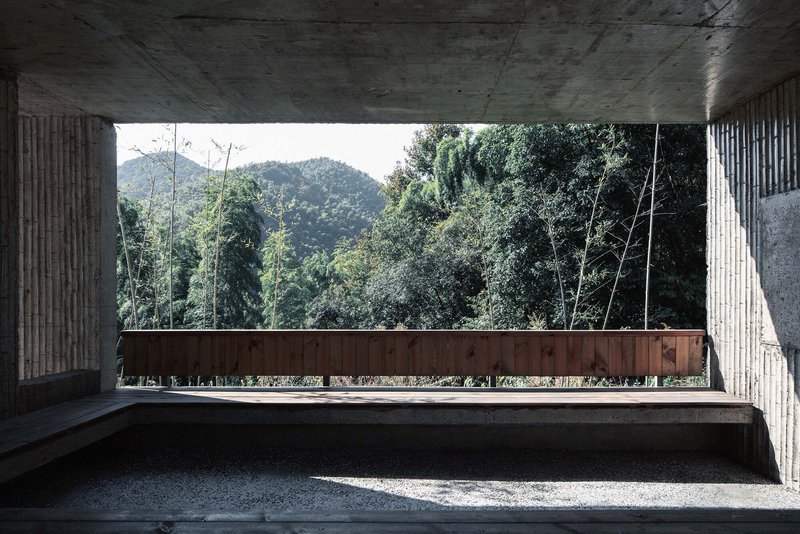 Concrete terrace framing a horizontal view of forested mountains through a sheltered opening