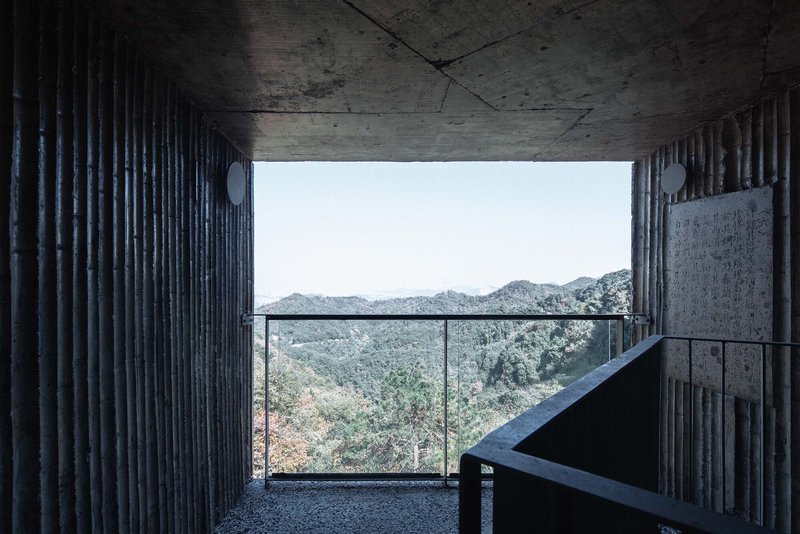 Concrete balcony with glass railing opening to distant mountain ridges under overcast sky