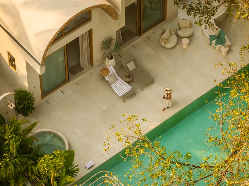 Overhead view of the courtyard terrace with person walking beside the pool at golden hour