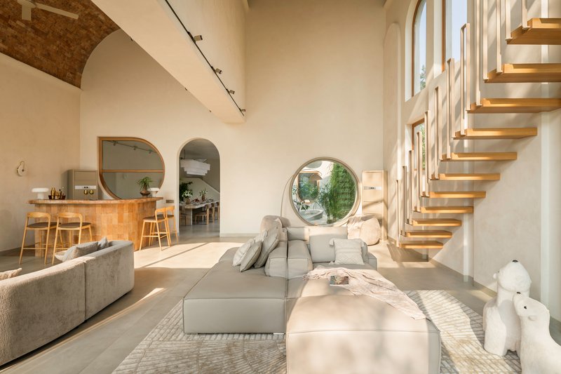 Interior view of the floating timber staircase beside a circular window overlooking the garden