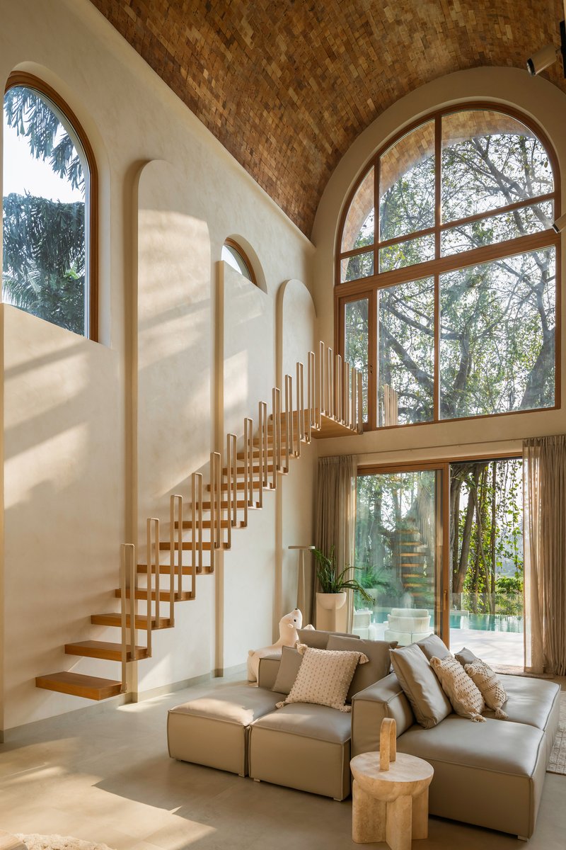 Living space beneath the vaulted brick ceiling showing the cantilevered staircase and full-height glazed openings