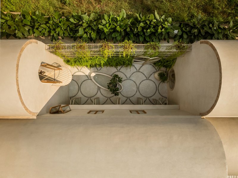 Top-down view through circular opening into courtyard with patterned paving and planted beds