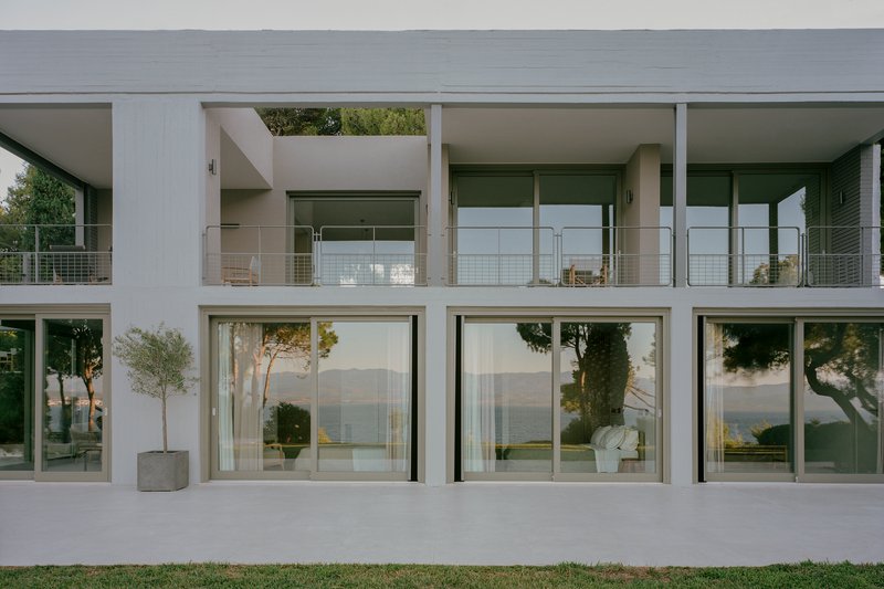 Courtyard terrace with floor-to-ceiling glazing and potted trees overlooking distant hills at dusk