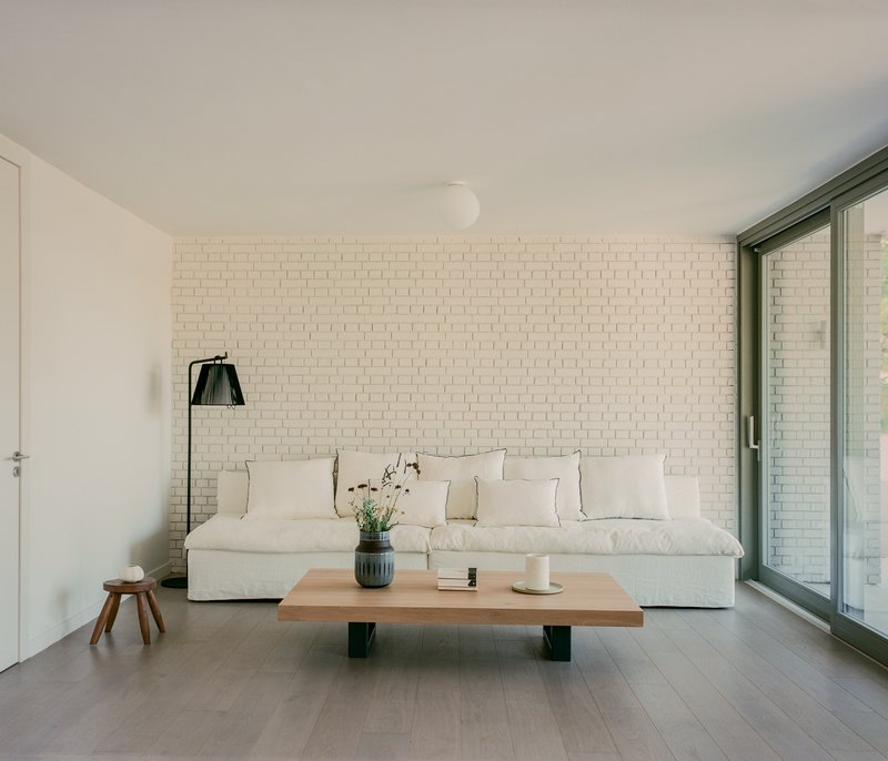 Living room with white brick wall, wood coffee table, and floor-to-ceiling sliding glass doors