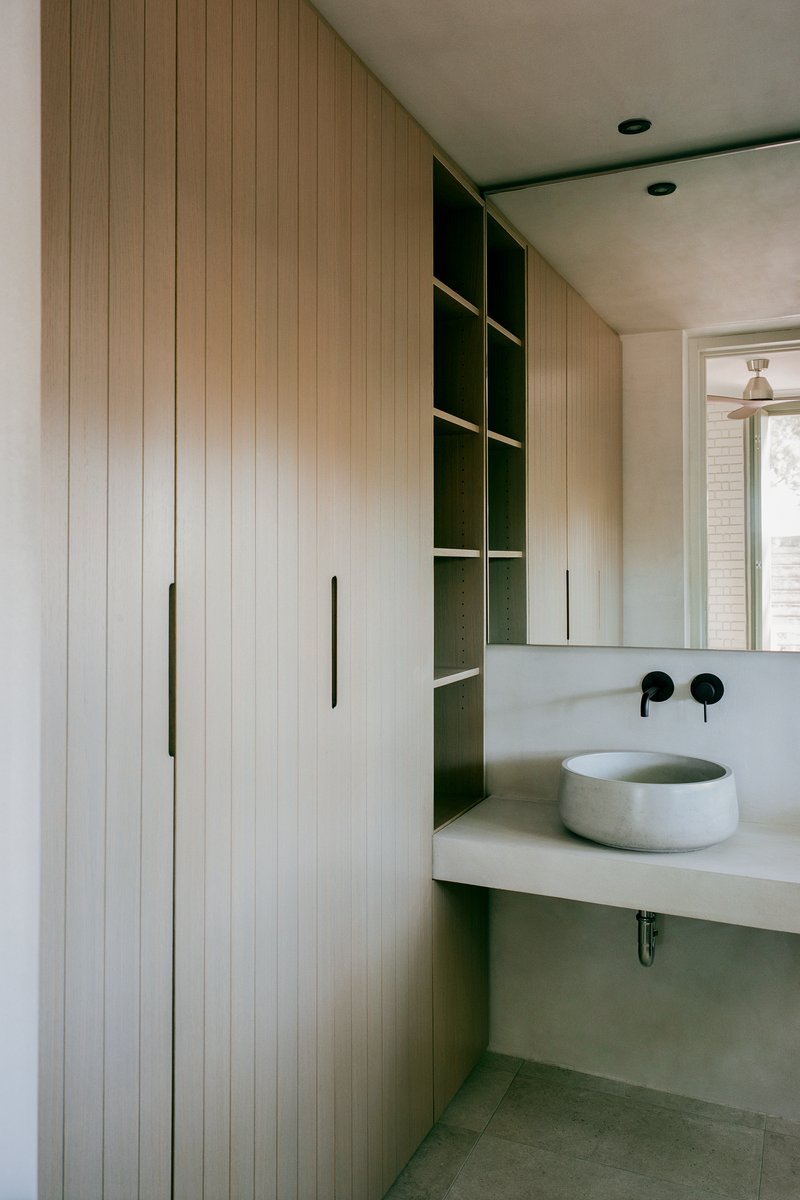 Bathroom vanity with timber cabinetry, open shelving and a round concrete vessel sink
