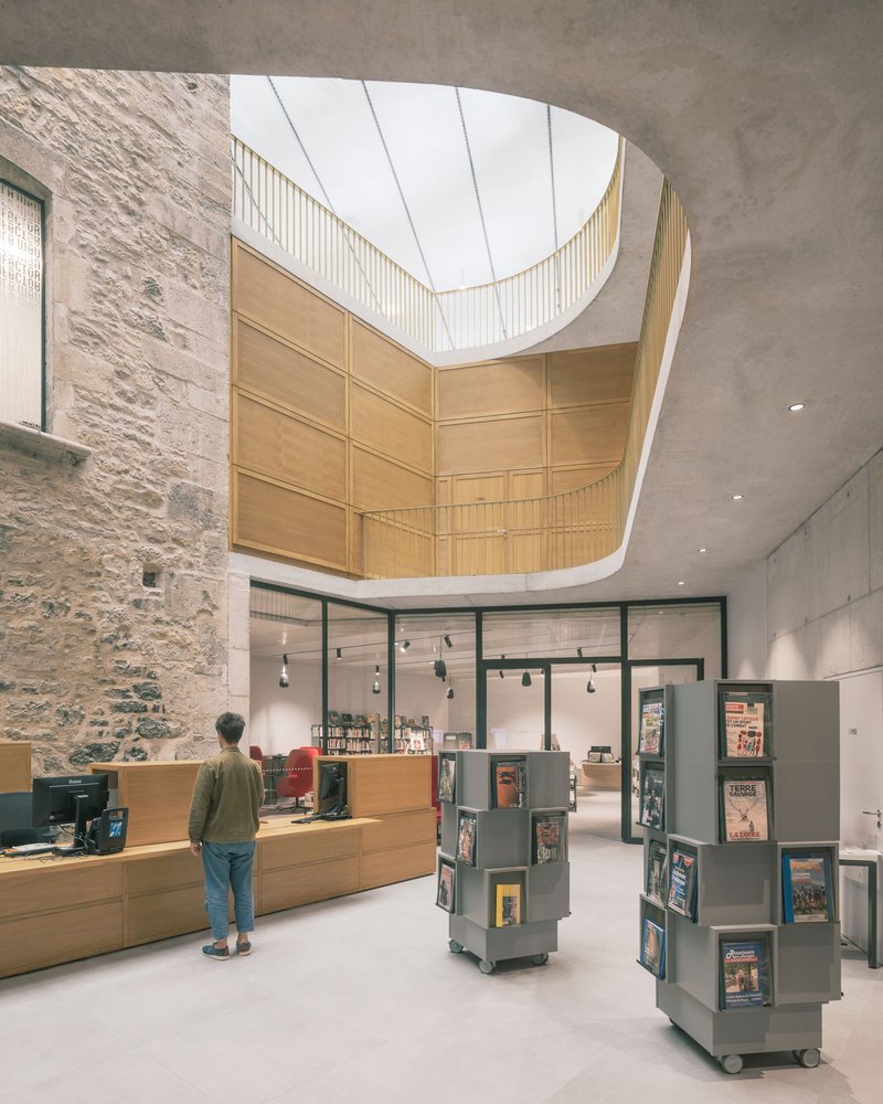 Interior atrium with curved timber skylight above a reception desk and rotating display towers for a visitor