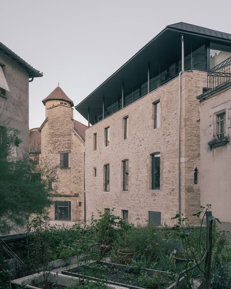 Exterior facade of stone building with new steel canopy and vegetable garden in foreground