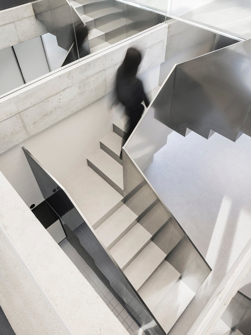 Top-down view of the zigzagging staircase with a figure ascending through the multi-level volume