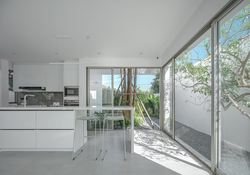 Open kitchen with sliding glass doors leading to a courtyard with a tree casting dappled shadows