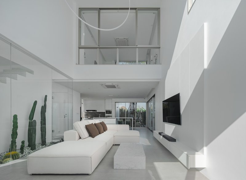 Open-plan living area looking toward kitchen with mezzanine window overlooking the interior volume