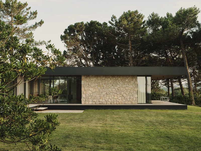 Garden elevation showing stone wall panel flanked by glazing beneath the flat roof overhang
