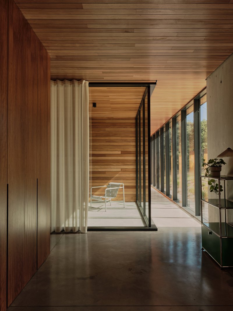 Corridor with timber cladding leading to a glazed door opening onto a private courtyard