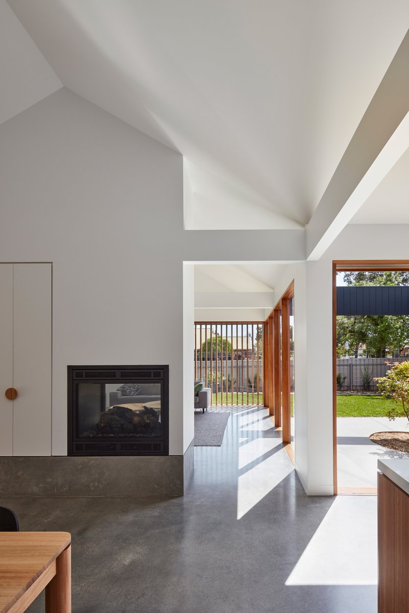 Living room interior with concrete fireplace base looking through to the garden courtyard in afternoon light