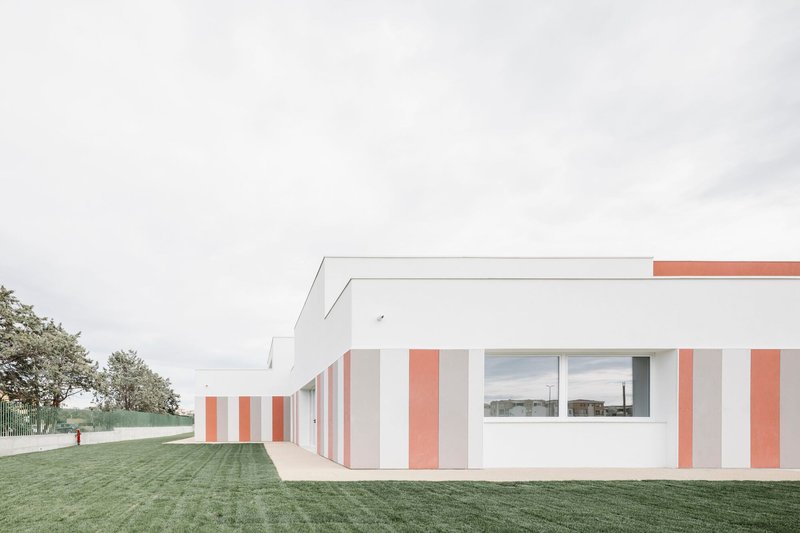 Side elevation showing the striped facade extending along a covered walkway beside a mown lawn