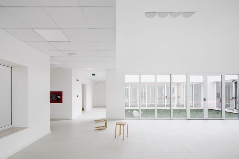 Open interior space with rhythmic glazed doors, drop ceiling panels, and two wooden stools