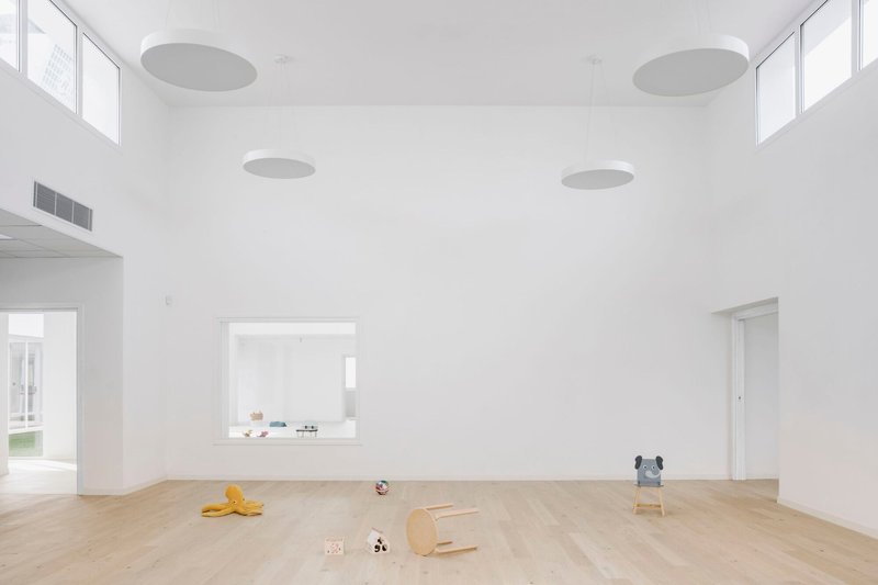 Double-height room with circular acoustic ceiling panels, light wood flooring, and high clerestory windows