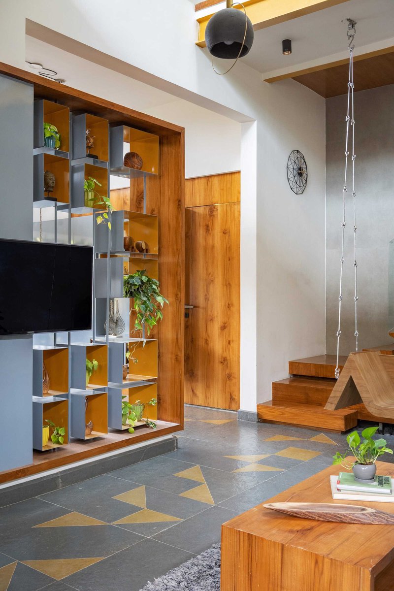 Double-height entry space with modular shelving unit, timber door, and suspended staircase with rope railings