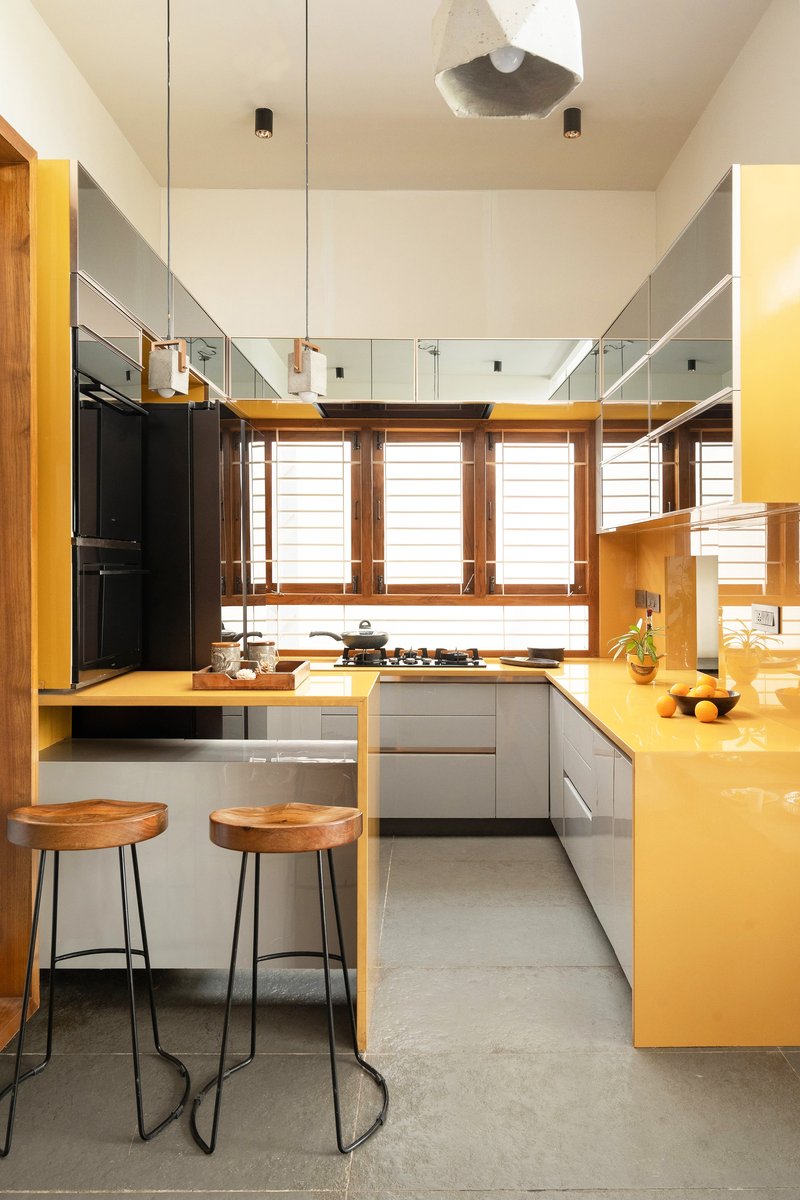 Kitchen with yellow countertops, timber-framed windows, glass mezzanine railing, and two wooden bar stools