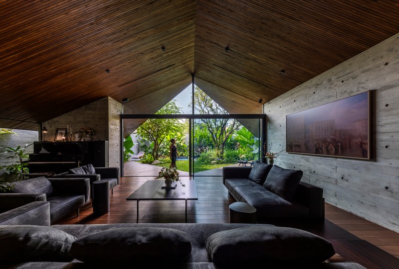 Living room with wood-slat ceiling and full-height glazing framing a view of the planted courtyard